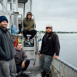 Four fishermen posing on deck of a fishing boat.