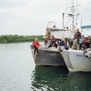 A group of fishermen posing on two boats side by side in the water.