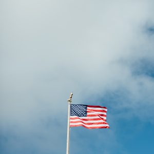 An American flag waving in a blue sky obstructed by clouds.
