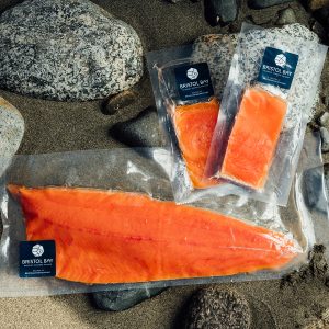Three packages of Bristol Bay Sockeye Salmon resting on rocks on a beach.