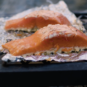 Close up of two sockeye salmon portions being cooked over a grill.