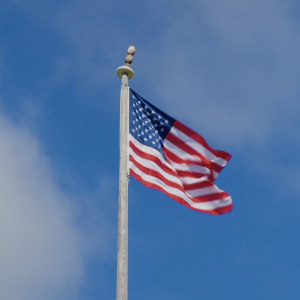 An American Flag flying against a blue sky dappled with cirrus clouds.