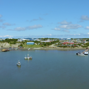 Video still of Bristol Bay with processing buildings in the background and boats in the water.