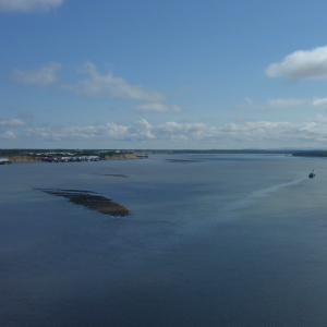 An expanse of water in Bristol Bay, one fishing vessel off in to the right in the distance, clouds hovering at the horizon.